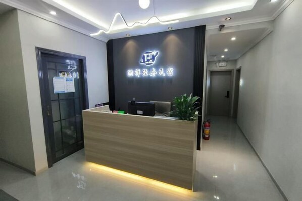 A reception desk with a logo, a plant, and a fire extinguisher. - Tianshun Apartment (Chongqing)