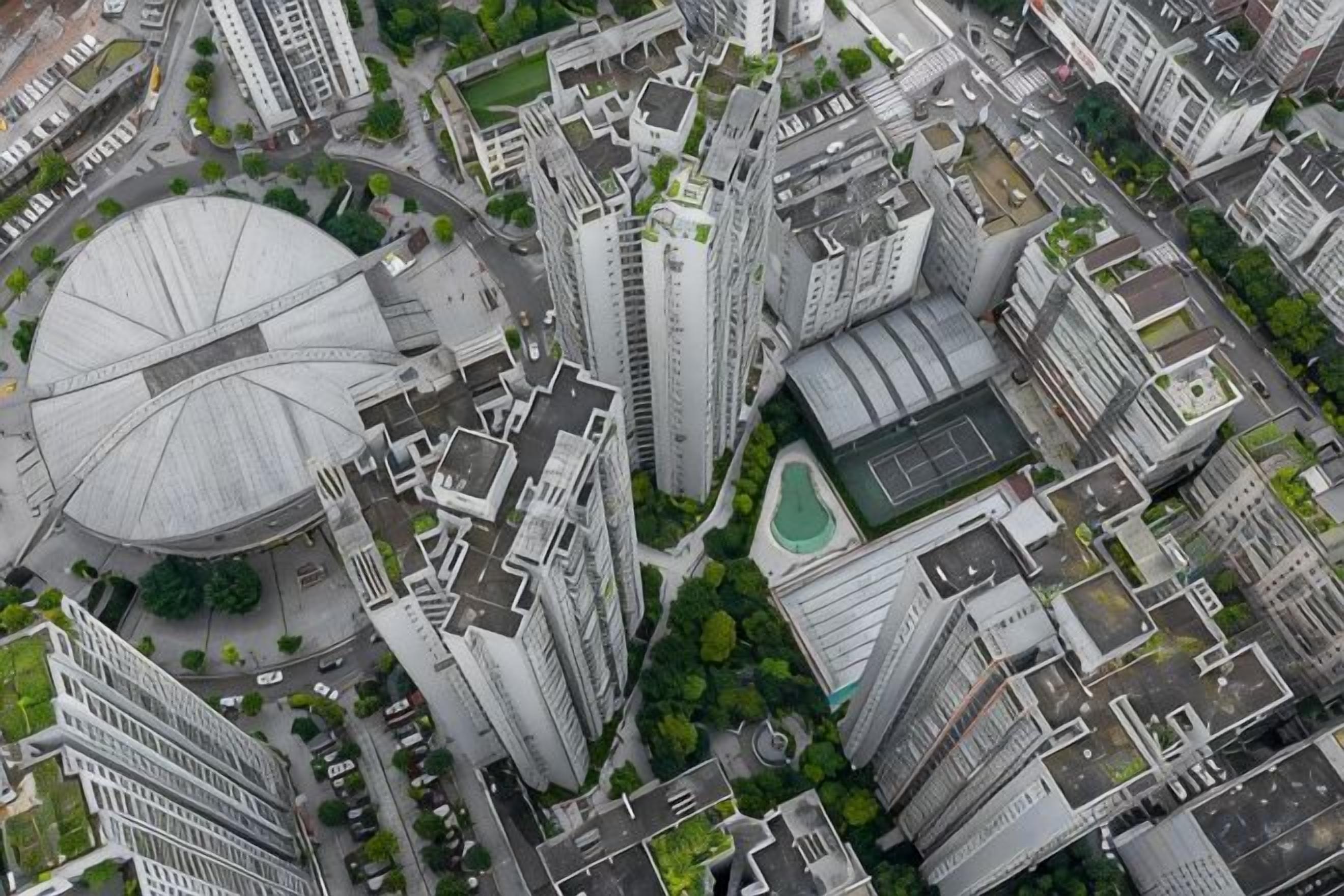 A high-rise building with a circular structure, surrounded by other tall buildings, indicating a dense urban area.