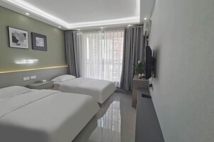 Quarto de hotel moderno com duas camas, televisão de tela plana e varanda com cortinas.