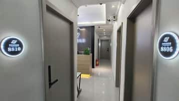 A hotel corridor with doors labeled 8810 and 8806, leading to a reception area with a plant and a fire extinguisher.