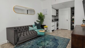 Una sala de estar moderna con un sofá gris, un tapete azul y una mesa de centro de vidrio.