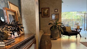 Una habitación con una mesa consola de madera, un jarrón grande, un sofá y una planta en maceta.