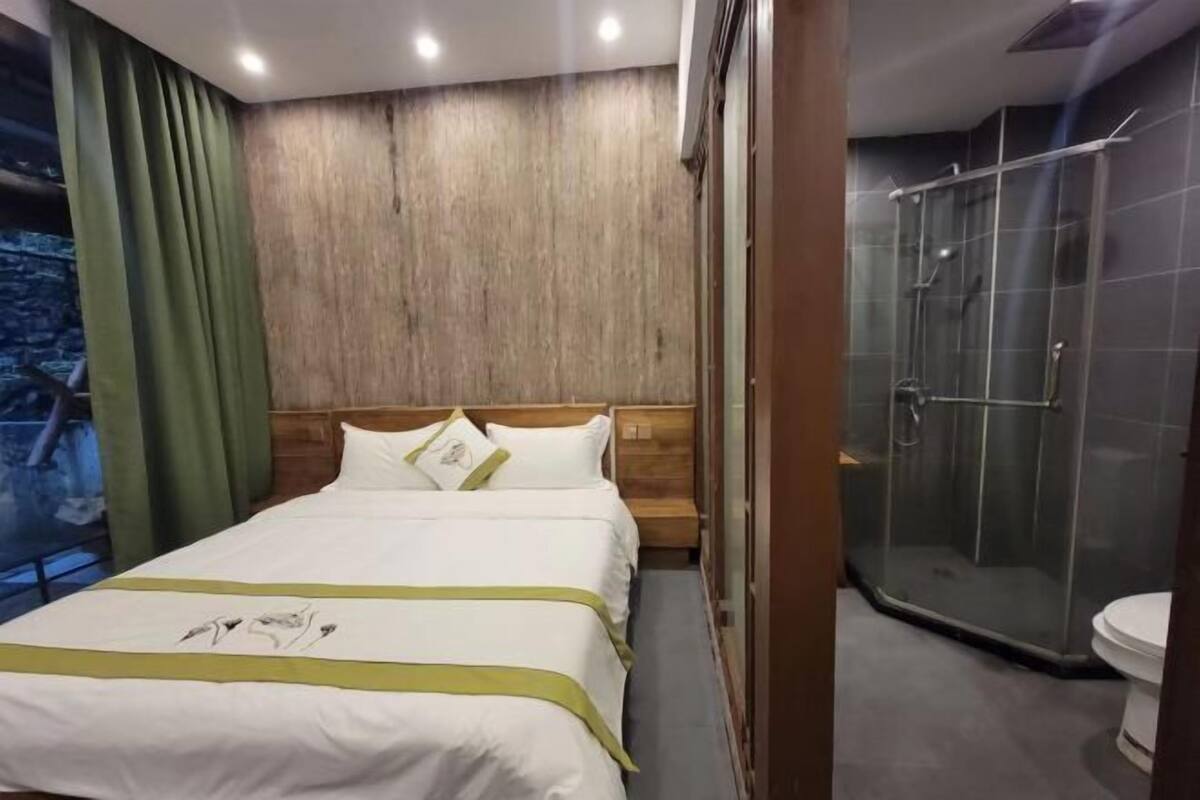 A hotel room with a bed, a shower, and a view of the outdoors.