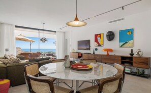 A modern living room with a round glass table, wicker chairs, a sofa, and a view of the sea. - Penthouse Casa Volver | Ref. #74 (Marbella)