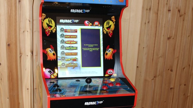 Una máquina de videojuegos Pac-Man con pantalla digital, palanca y botones.