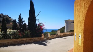A coastal road with stone walls, cypress trees, and a building with a yellow facade. - Casa Looma Splash in the lovely swimming pool (Benitachell)
