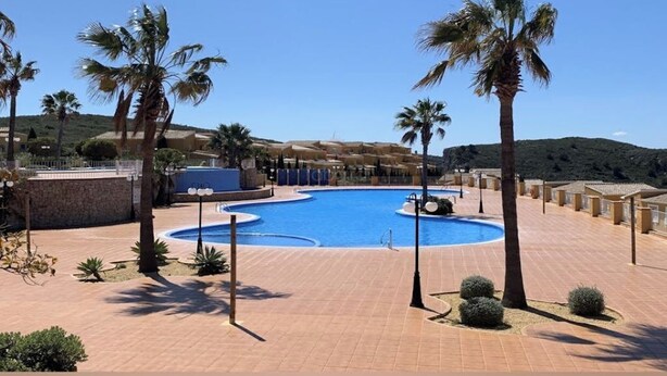 A pool area with palm trees, a clear blue sky, and a hilly landscape in the background. - Casa Looma Splash in the lovely swimming pool (Benitachell)