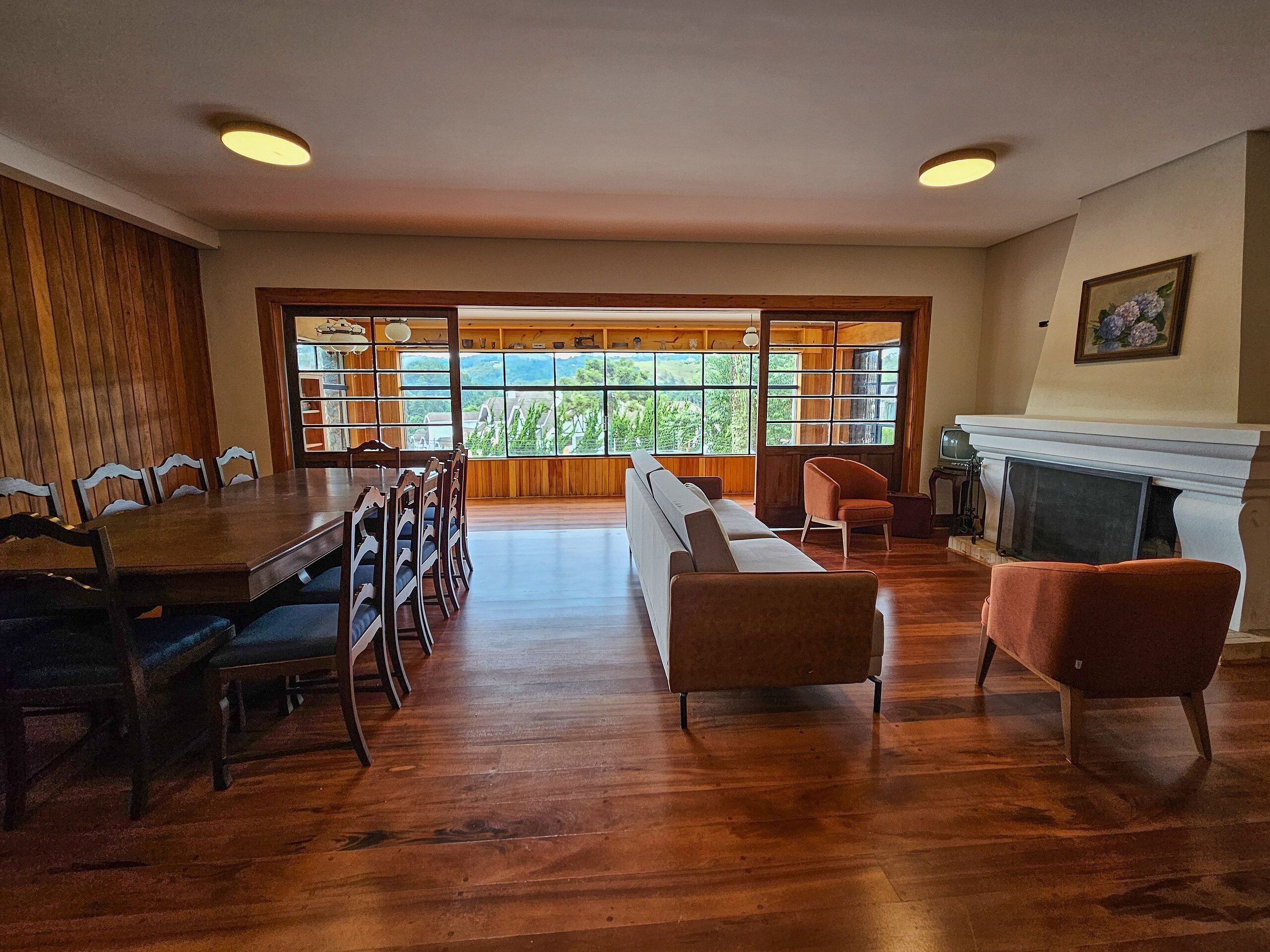 A spacious living room with a wooden dining table, a sofa, and a fireplace.