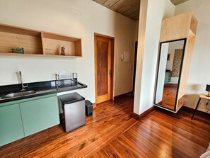 Eine moderne Küche mit Holzboden, einer eingebauten Spüle und einem kompakten Kühlschrank.