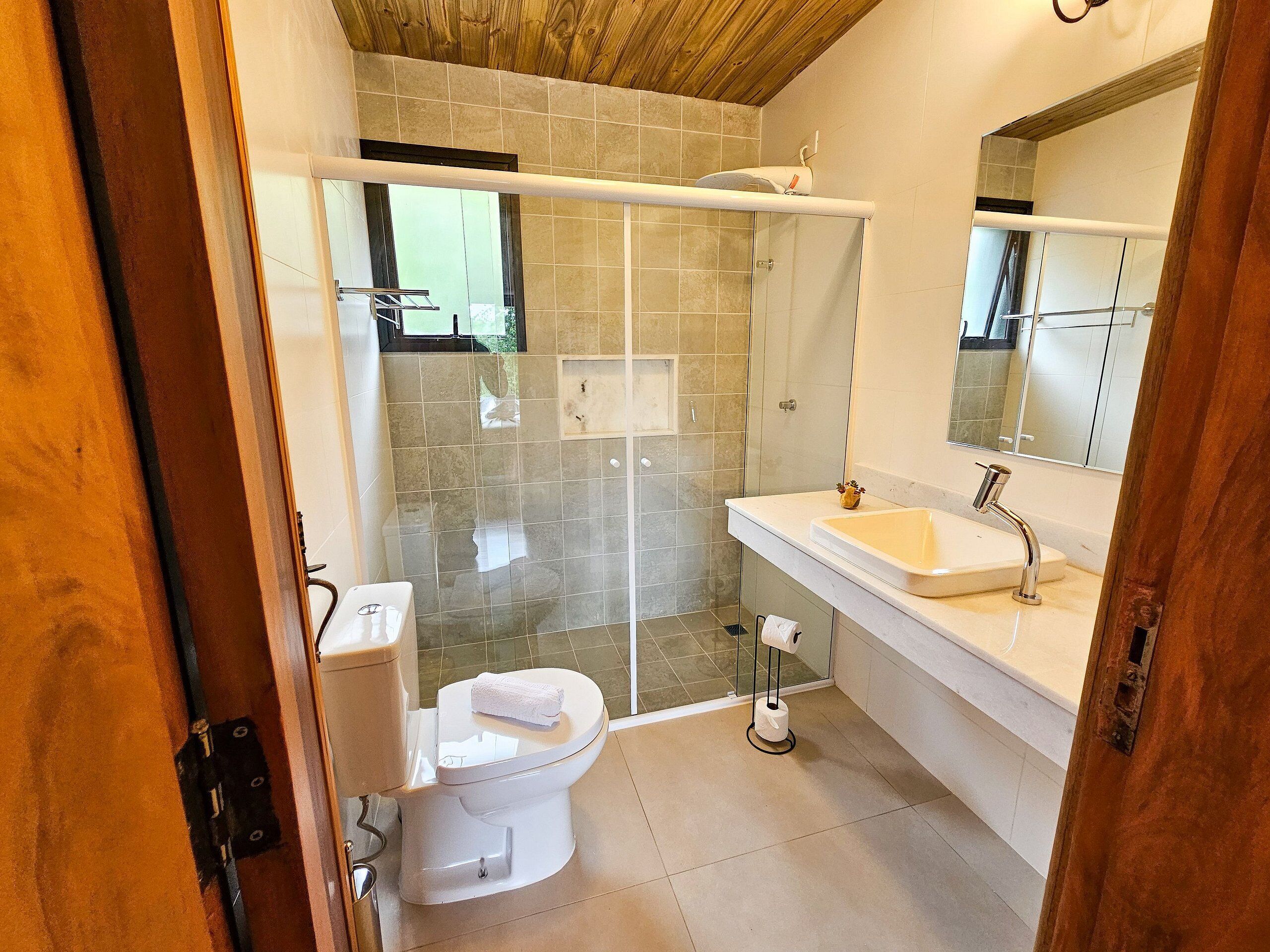Un bagno moderno con cabina doccia in vetro, un water bianco e un lavandino con specchio sopra.