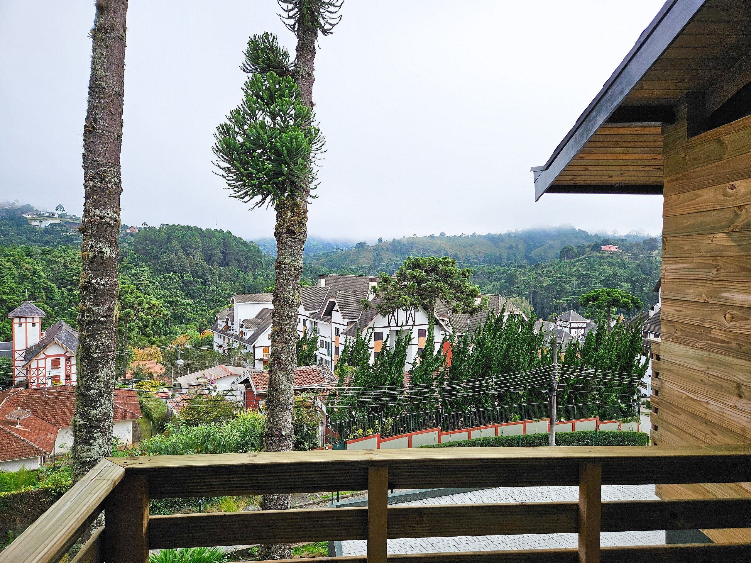 A wooden deck overlooking a village with traditional houses and a hill in the background.
