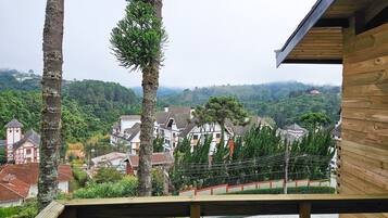 A wooden deck overlooking a village with traditional houses and a hill in the background.