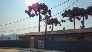 A building with a fenced exterior, a sign indicating 'STUDIOS CAPAVARI 2019', and a clear sky. - Estudios no Capivari by The Lodges (Campos do Jordão)