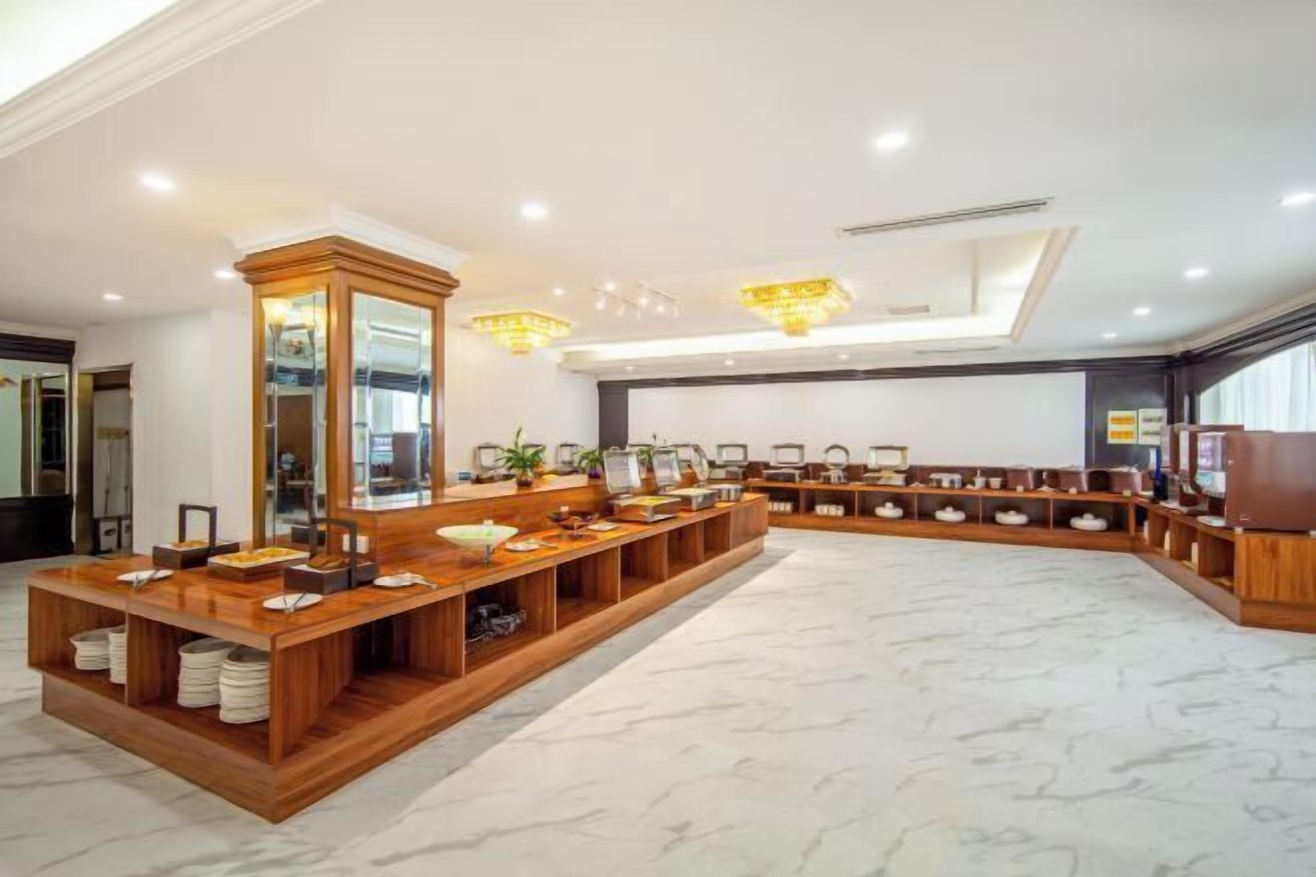 A modern hotel lobby with a long reception desk, wooden shelving, and a marble floor.