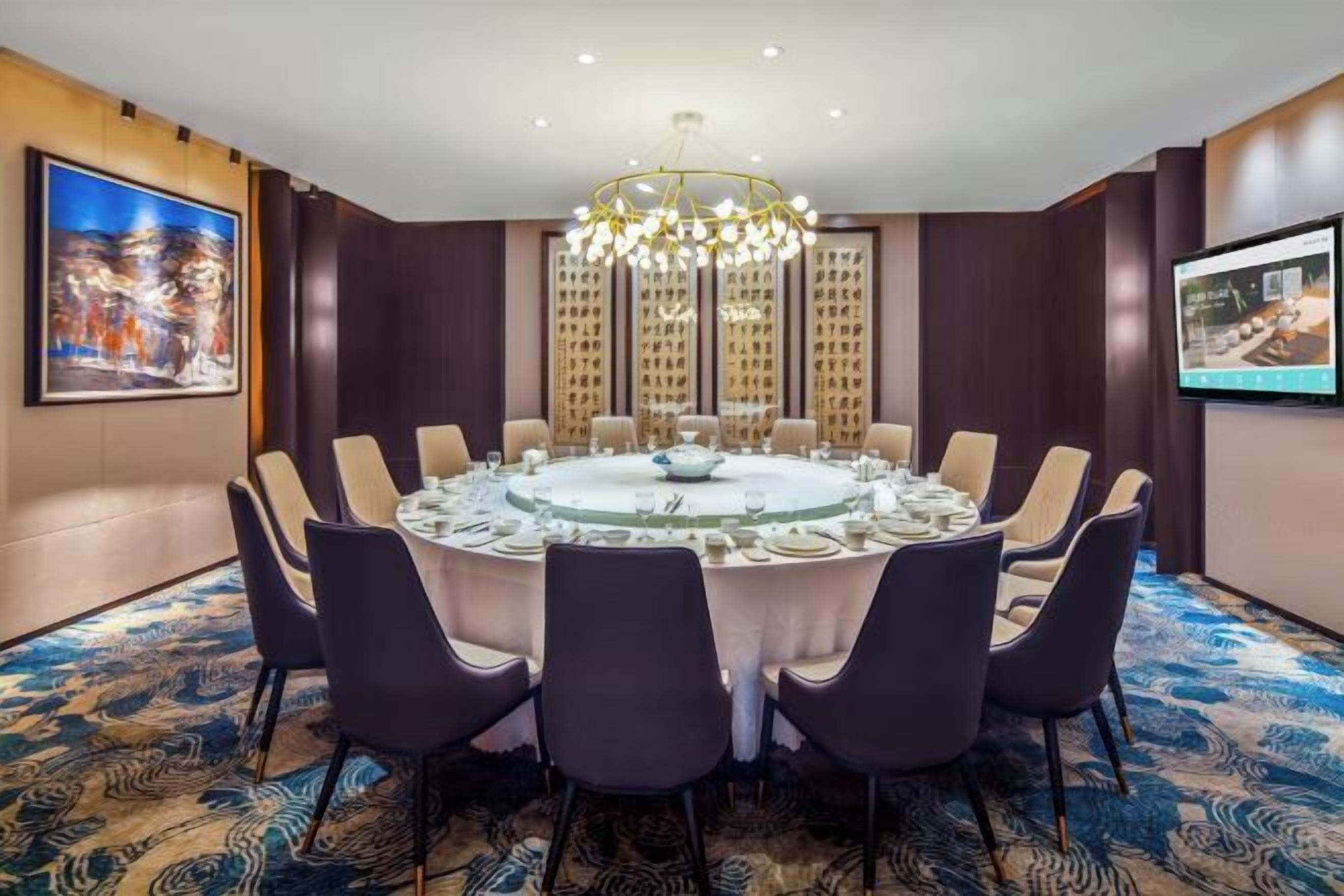 Una sala conferenze con un tavolo rotondo, sedie e un lampadario.