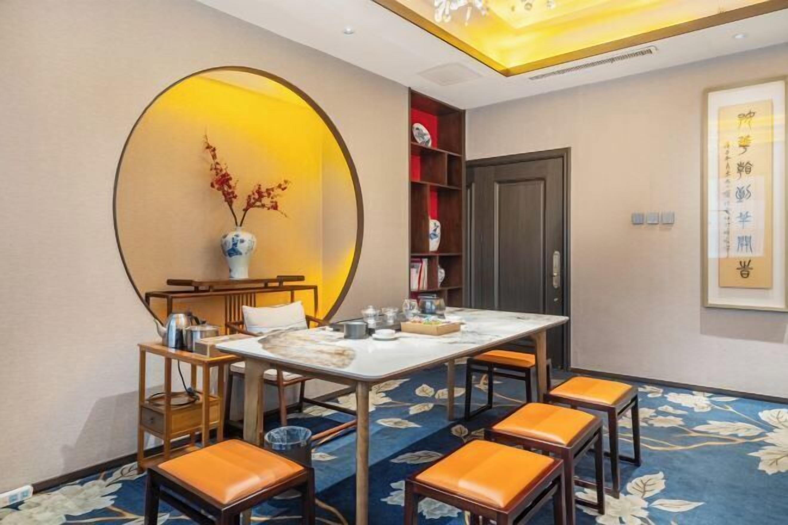 Uma área de refeições com mesa redonda, cadeiras e um detalhe decorativo na parede.
