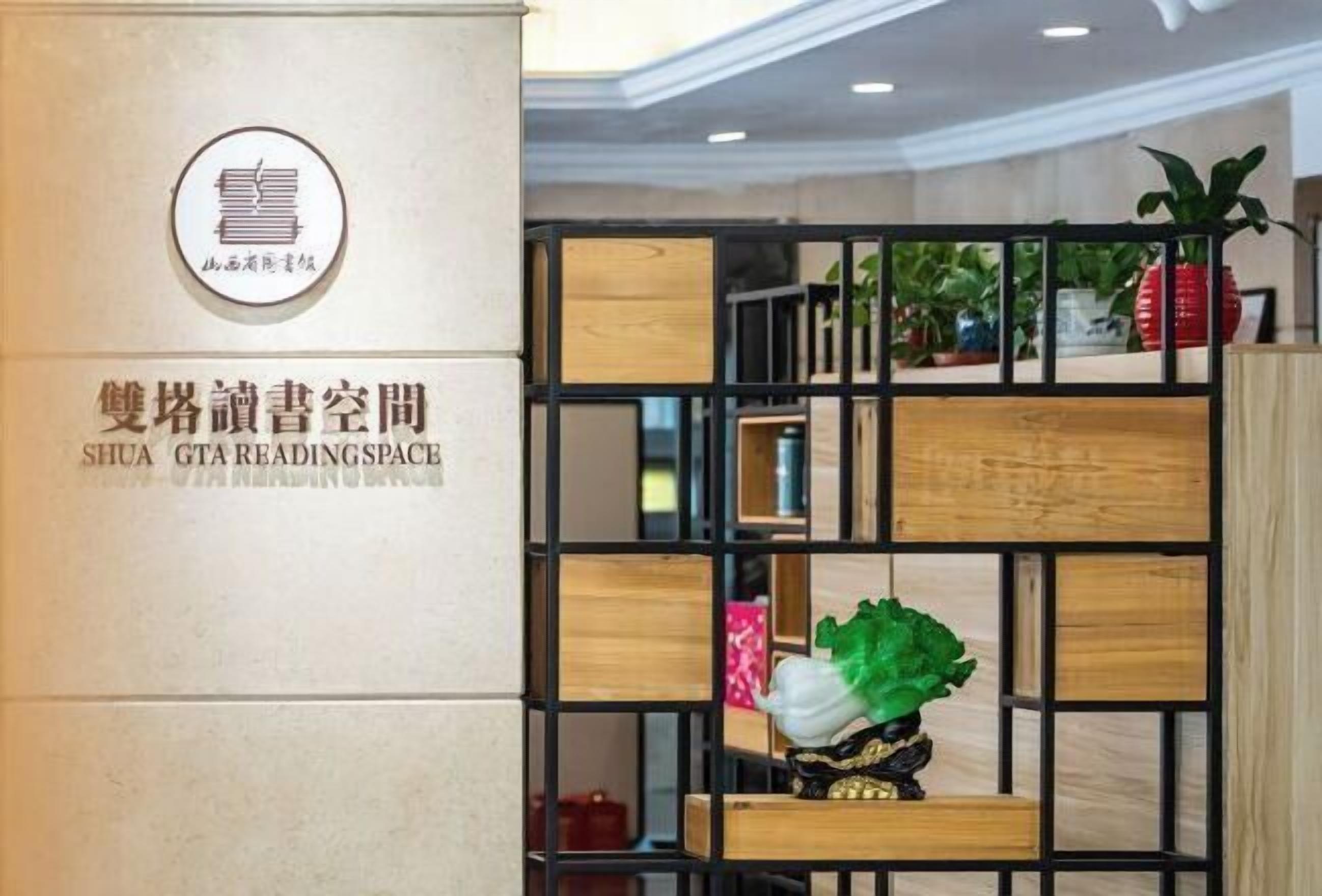 A reading space with a sign in both Chinese and English, a decorative plant, and a black metal partition.