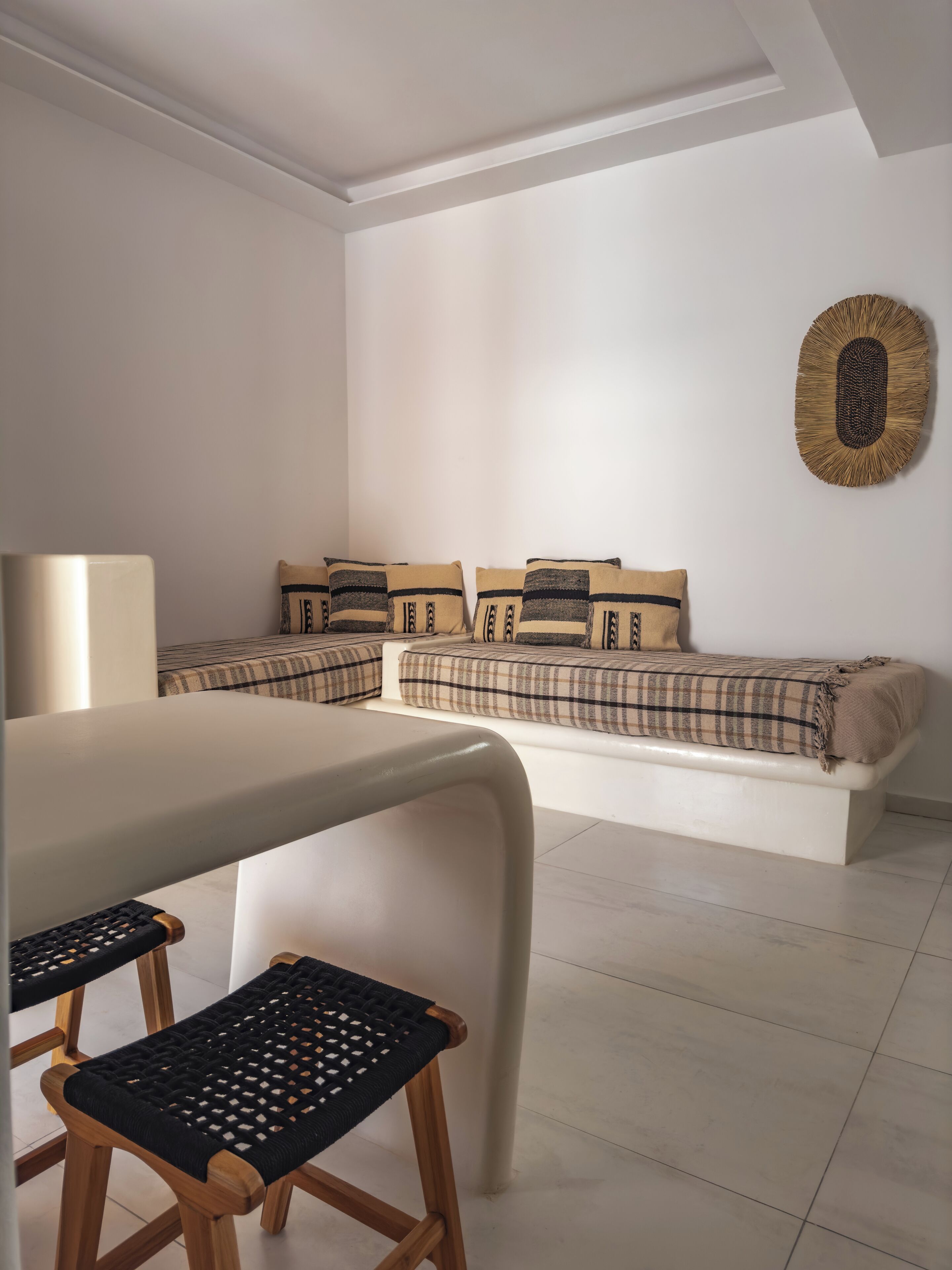 A modern living room with a sofa set, a coffee table, and two wooden chairs with woven seats.
