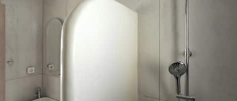 Een moderne badkamer met een douche, een wastafel en een spiegel.