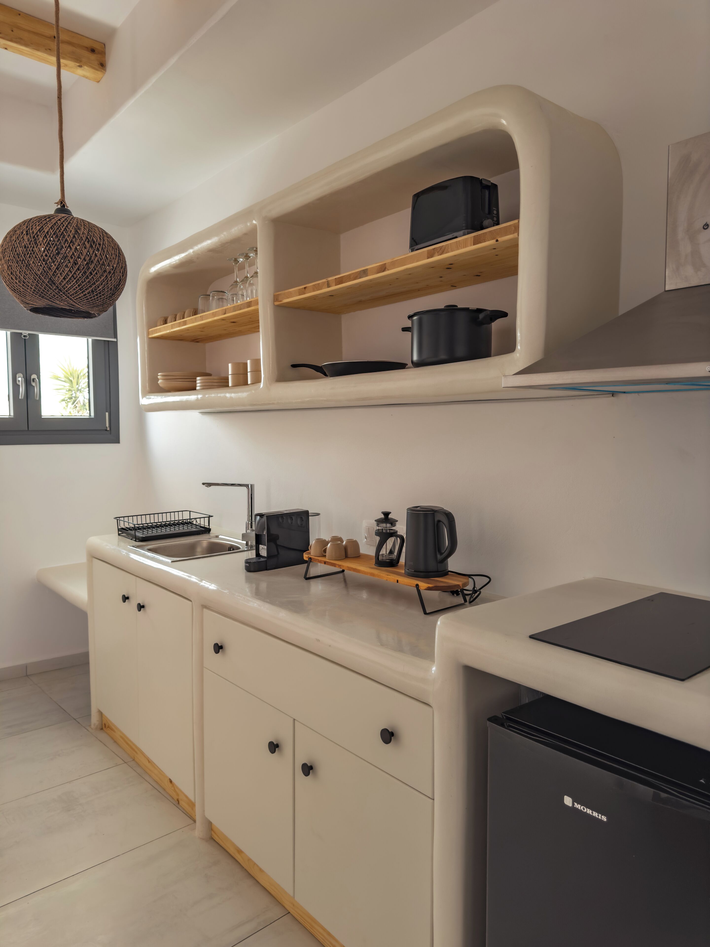 A modern kitchen with white cabinetry, a black refrigerator, and wooden shelves above the counter.