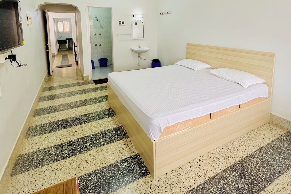 Ein Hotelzimmer mit Bett, Deckenventilator, Waschbecken und Spiegel.
