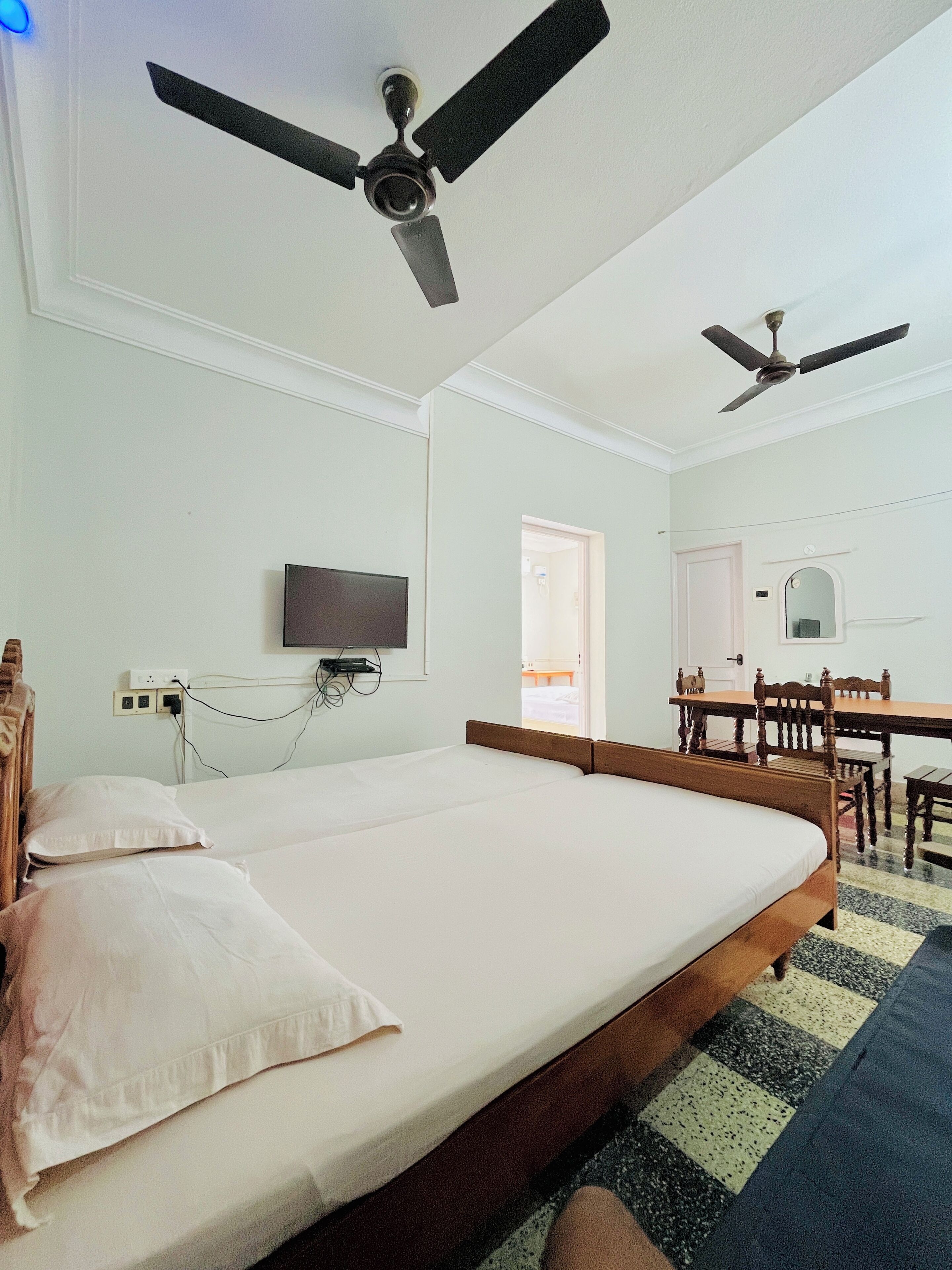 Camera da letto con un letto, una scrivania, una sedia e due ventilatori a soffitto.
