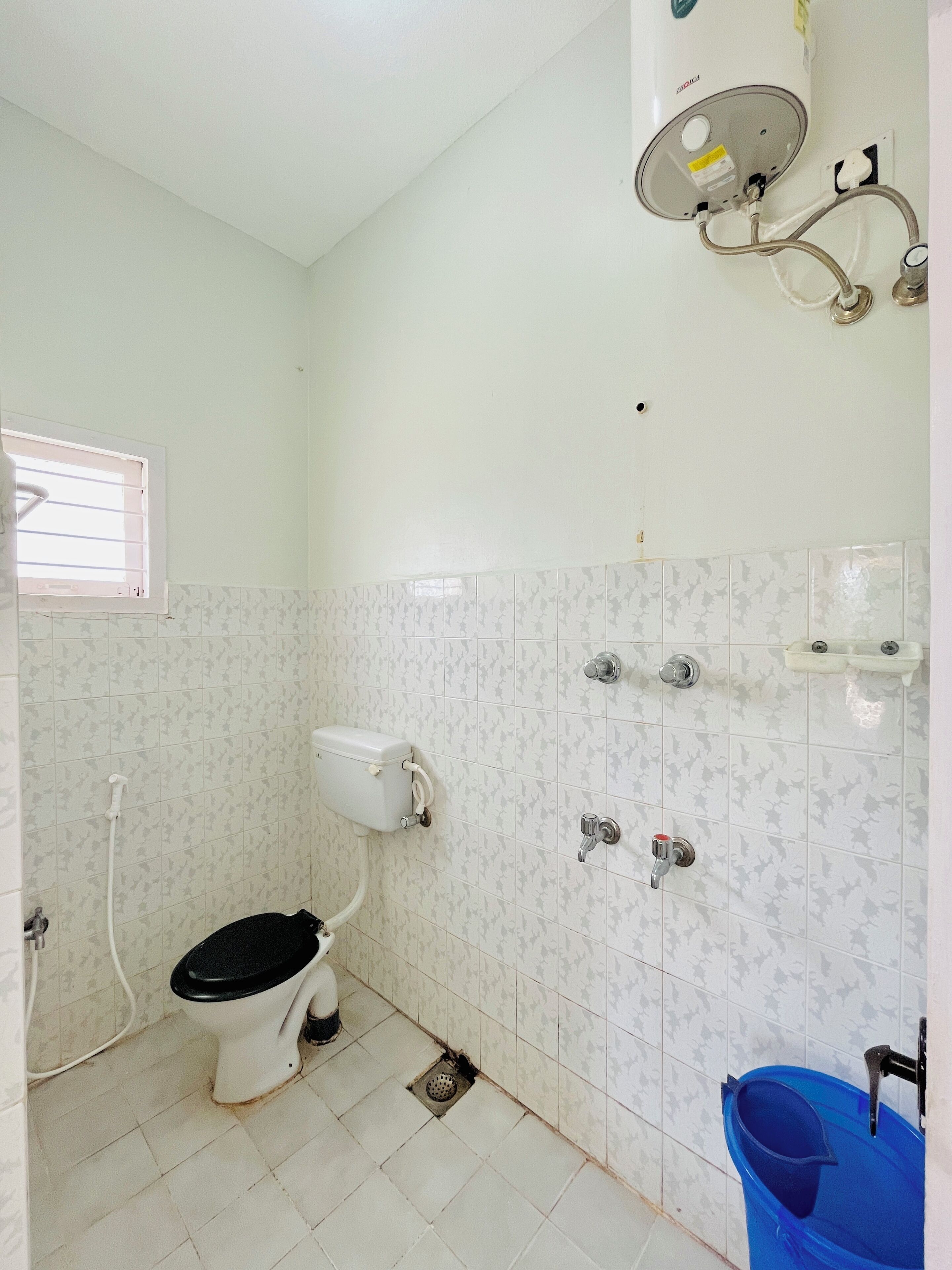 A small, basic bathroom with a toilet, a shower, and a sink.