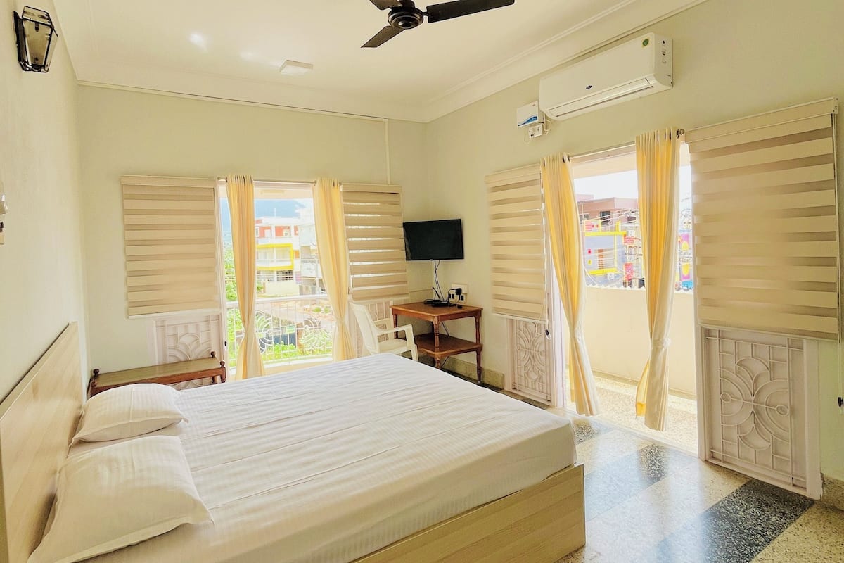 Ein Hotelzimmer mit Bett, Schreibtisch, Deckenventilator und Blick ins Freie.