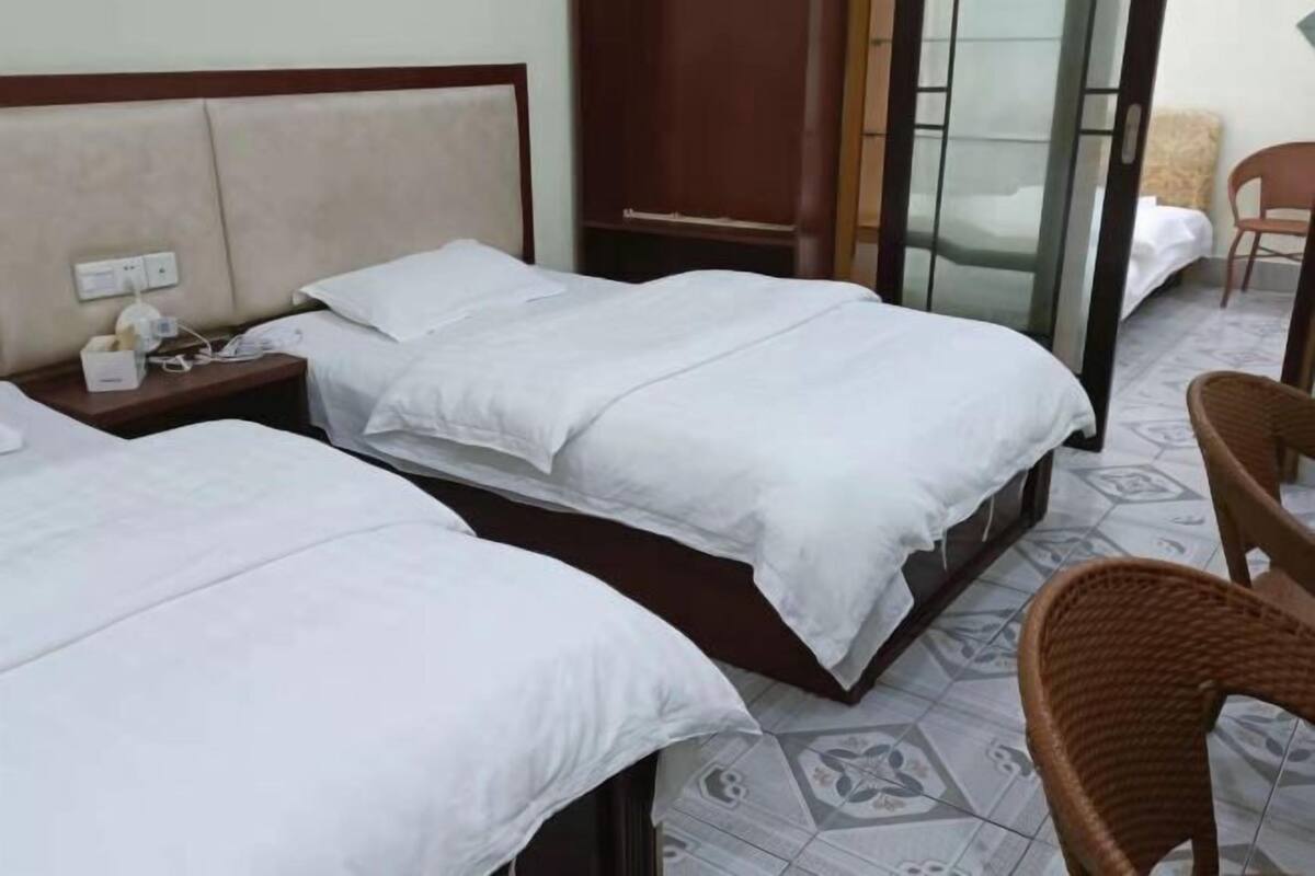 Ein Hotelzimmer mit zwei Betten, einem Nachttisch, einem Sessel und einem Kleiderschrank.