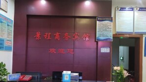 A reception desk with a dark counter, a red telephone, and a sign with text. - Anyuan Jingcheng Business Hotel (Anyuan)