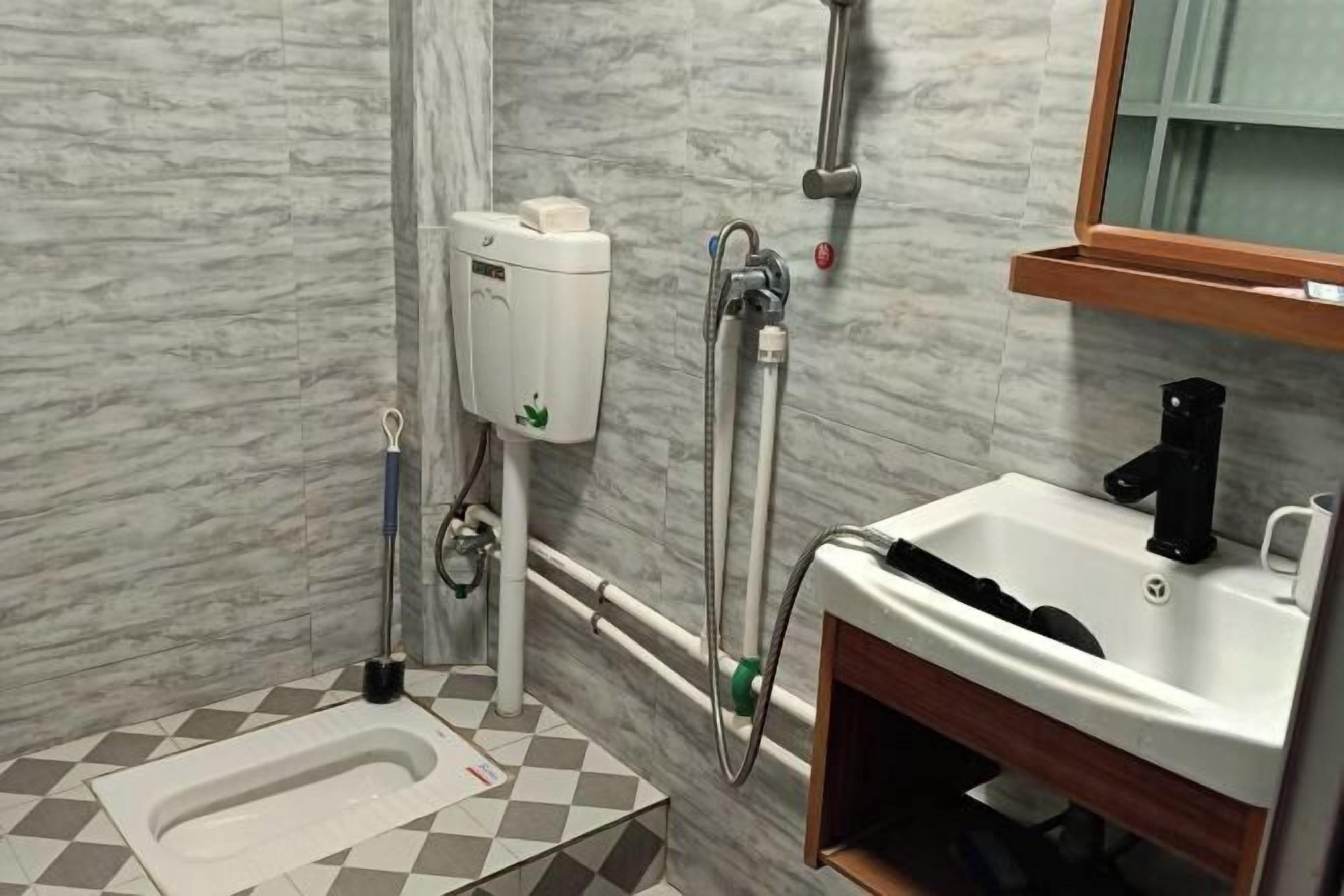 A bathroom with a toilet, bidet, sink, and marble walls.