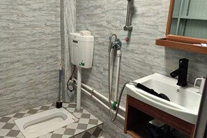 A bathroom with a toilet, bidet, sink, and marble walls.