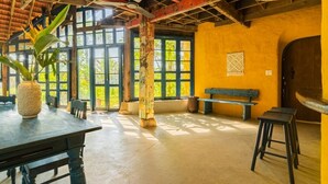 A spacious room with a large window, a wooden table, and a bench. - Flow House 3BR Oceanview An Bang Beach  (Da Nang)