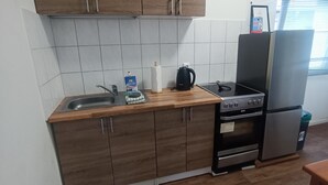 Una cucina con mobili in legno, un lavello in acciaio inox, una macchina da caffè, un fornello e un frigorifero.
