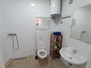 A small bathroom with a toilet, a sink, a shower, and a mirror. - Hostel Gransee (Gransee)