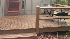 Una casa moderna con terraza de madera, una puerta roja y una corona en la pared.