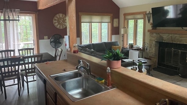 Una cocina con una isla grande, una zona de comedor con sillas, una chimenea y un televisor.