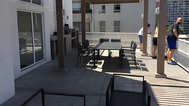 An outdoor patio area with a table and chairs, large windows, and a view of the cityscape. - Apartamento Urbano en Santiago (Santiago)