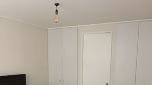 A bedroom with a bed, a nightstand, a TV, and a wardrobe. - Apartamento Urbano en Santiago (Santiago)