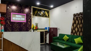 A hotel reception area with a neon sign reading "HOTEL HEAVEN STAY," a reception desk, a green sofa, and a patterned wall. - Hotel Heaven Stay (Shankarpalle)