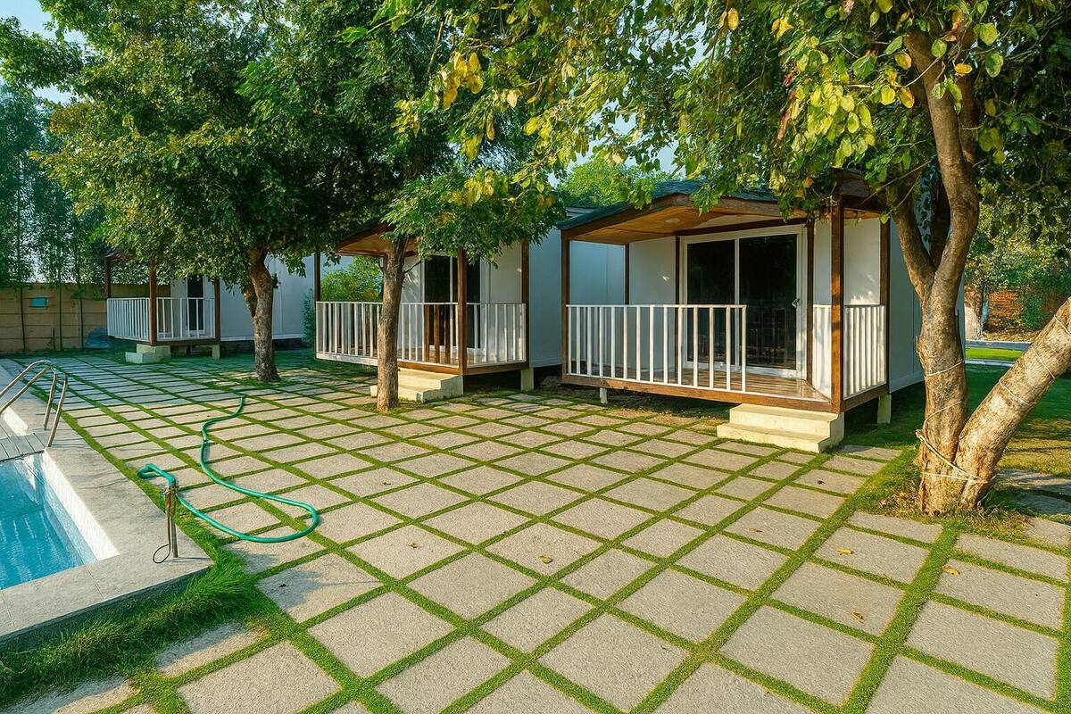 A backyard with a swimming pool, two covered seating areas, and a hose.