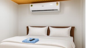 A hotel room with a bed, a remote control, and an air conditioning unit on the wall. - Hotel Heaven Stay (Shankarpalle)