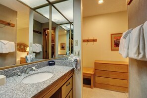 A bathroom with a granite countertop sink, wooden vanity, and a large mirror. - Penthouse in Center Village, Extra Sleeping Area, Amazing views. (Copper Mountain)