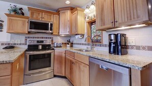 A kitchen with wooden cabinets, stainless steel appliances, a granite countertop, and a tiled backsplash. - Penthouse in Center Village, Extra Sleeping Area, Amazing views. (Copper Mountain)