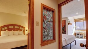 A hotel room with two beds, a wooden headboard, a stained glass window, and a desk with a chair. - Penthouse in Center Village, Extra Sleeping Area, Amazing views. (Copper Mountain)