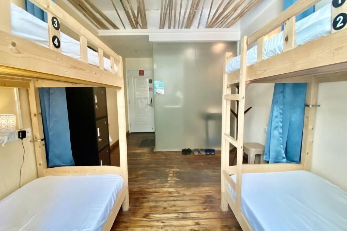 Een slaapkamer met stapelbed, een houten vloer en een deur naar een badkamer.