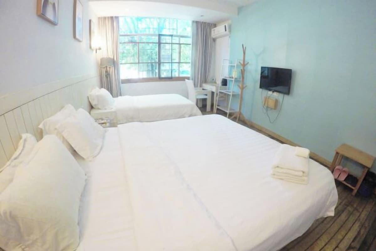 Een hotelkamer met twee bedden, een bureau, een televisie en een raam met gordijnen.