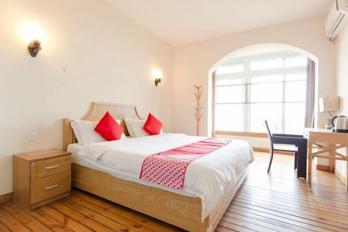 Een slaapkamer met een houten bed, een nachtkastje, een bureau en een stoel.