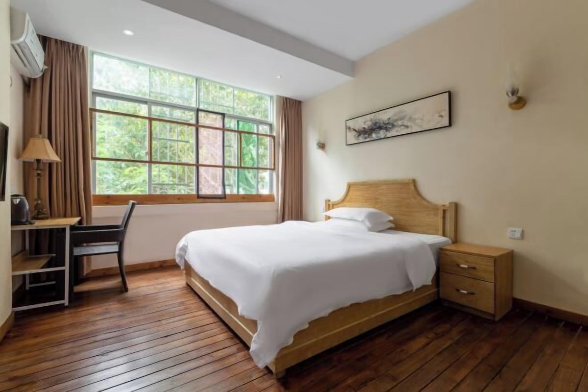 Een slaapkamer met een houten bed, een bureau en een stoel.