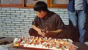 Jemand grillt Austern auf einem Grill.